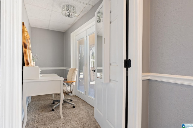 carpeted office with a paneled ceiling