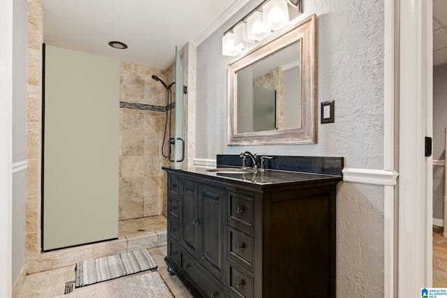 bathroom with a tile shower and vanity