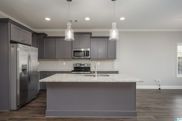 kitchen featuring appliances with stainless steel finishes, hanging light fixtures, and a kitchen island with sink