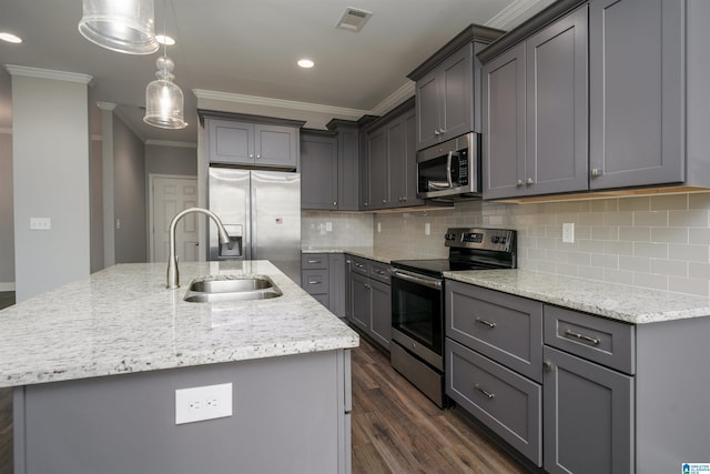 kitchen featuring appliances with stainless steel finishes, gray cabinetry, sink, a center island with sink, and decorative light fixtures