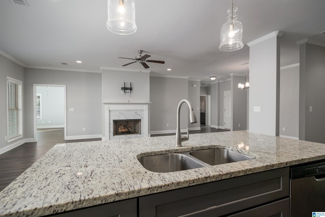 kitchen featuring light stone countertops, crown molding, sink, dishwasher, and hanging light fixtures