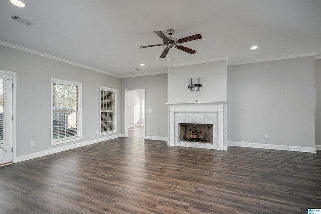 unfurnished living room with crown molding, dark wood-type flooring, ceiling fan, and a premium fireplace