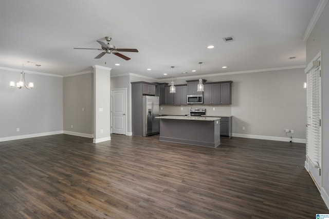 kitchen featuring appliances with stainless steel finishes, backsplash, gray cabinetry, a center island with sink, and hanging light fixtures