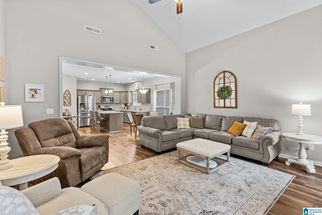 living room with ceiling fan, hardwood / wood-style floors, and high vaulted ceiling