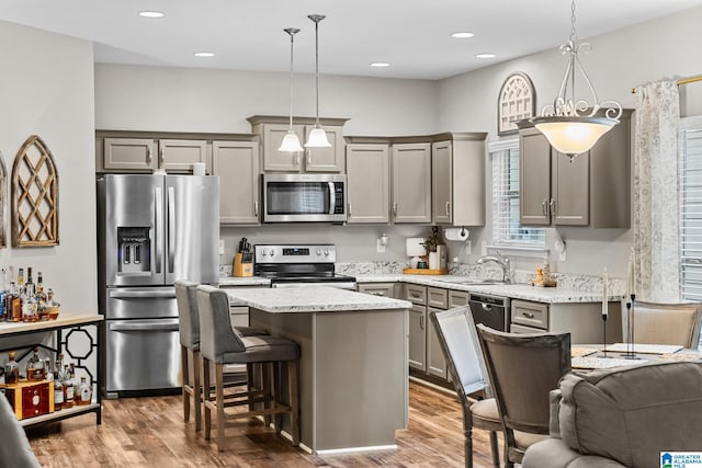 kitchen featuring light stone countertops, stainless steel appliances, hanging light fixtures, and a kitchen island