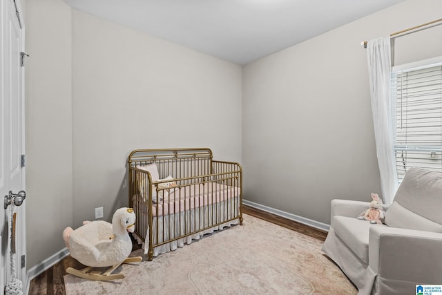 bedroom featuring hardwood / wood-style flooring, multiple windows, and a crib