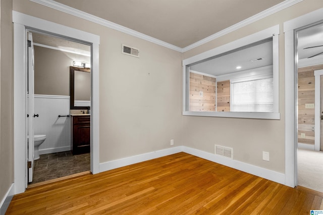 unfurnished bedroom with crown molding, ensuite bath, and wood-type flooring