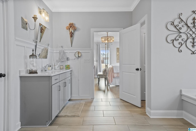 bathroom with an inviting chandelier, ornamental molding, and vanity