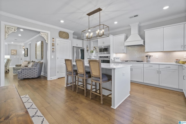 kitchen with appliances with stainless steel finishes, custom exhaust hood, white cabinets, and a center island