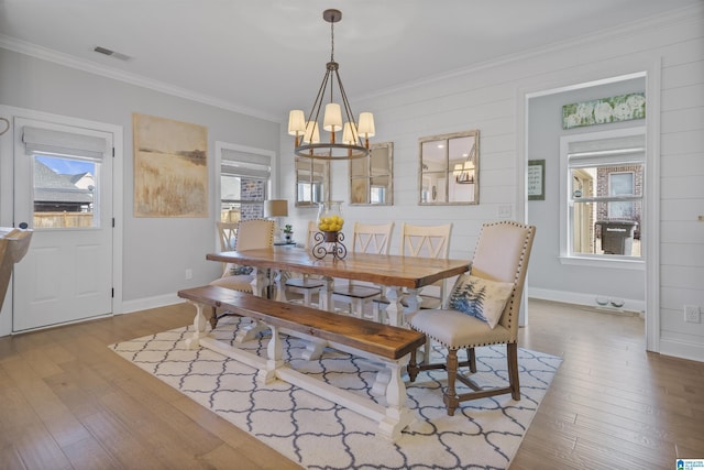 dining room featuring plenty of natural light, crown molding, a chandelier, and hardwood / wood-style floors