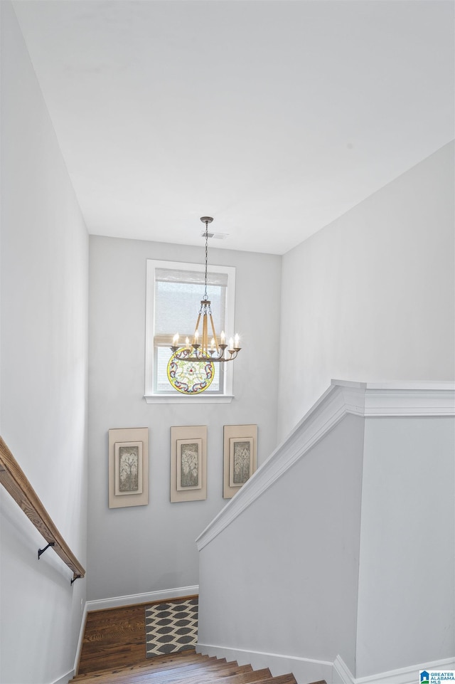 staircase featuring an inviting chandelier and hardwood / wood-style flooring