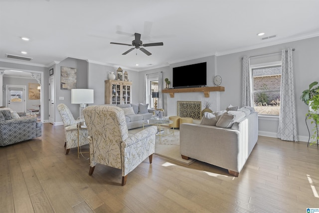 living room featuring ceiling fan, ornamental molding, and light hardwood / wood-style flooring