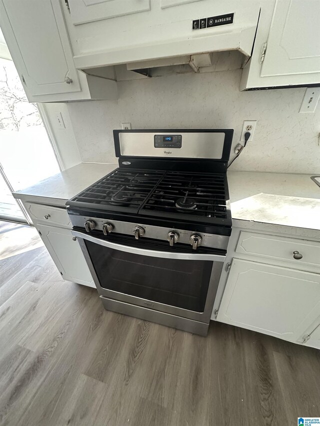 kitchen featuring light hardwood / wood-style floors, white cabinetry, and stainless steel gas range