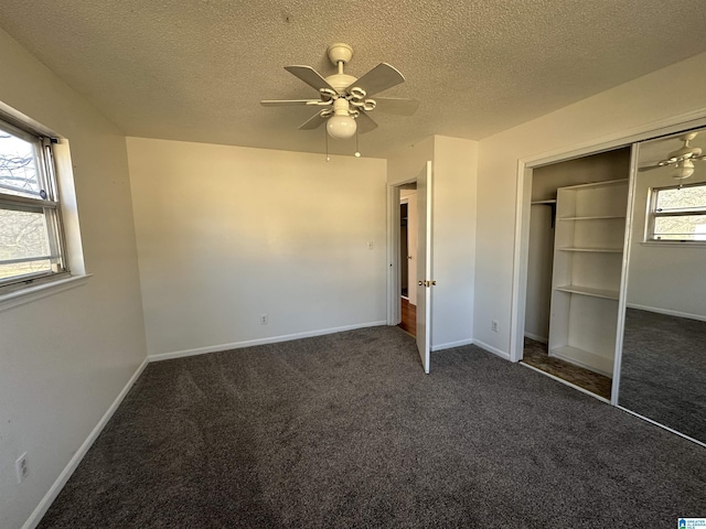 unfurnished bedroom with ceiling fan, multiple windows, a closet, and dark colored carpet