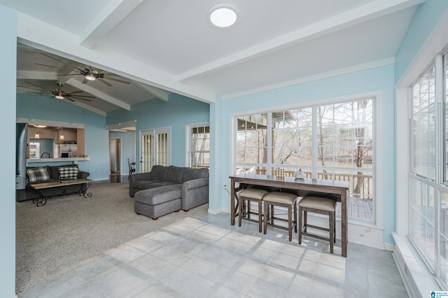 living room with ceiling fan, light colored carpet, vaulted ceiling with beams, and plenty of natural light