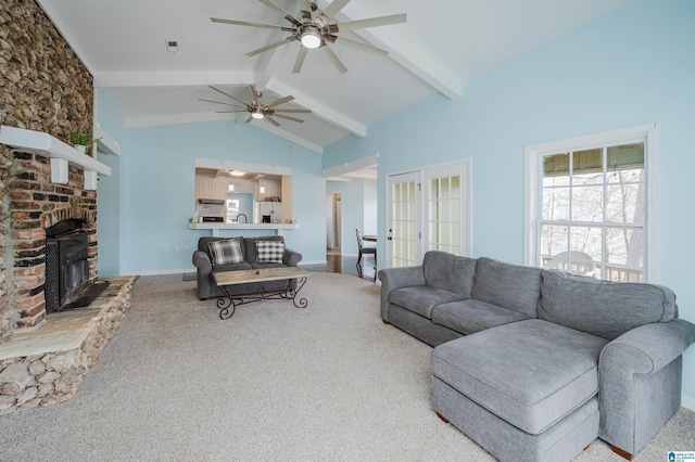 carpeted living room featuring ceiling fan, french doors, vaulted ceiling with beams, and a wood stove