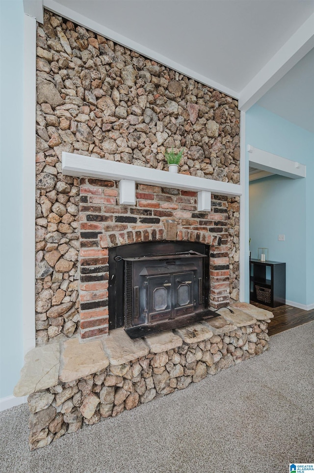 room details featuring beamed ceiling, carpet floors, and a wood stove