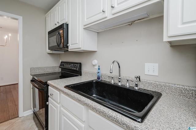 kitchen with black appliances, light tile patterned flooring, white cabinetry, and sink