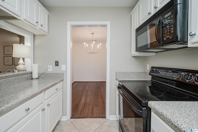 kitchen featuring white cabinets, black appliances, light tile patterned floors, and a notable chandelier