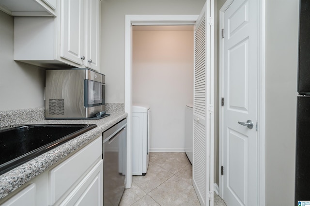 kitchen with light stone countertops, white cabinetry, stainless steel dishwasher, and light tile patterned flooring