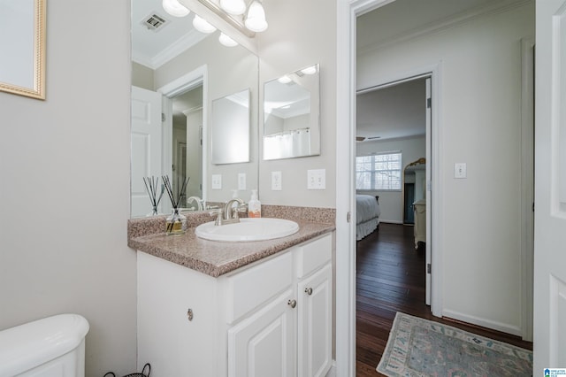 bathroom featuring vanity, toilet, wood-type flooring, and crown molding