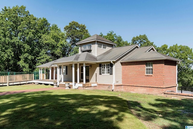 rear view of property featuring a porch and a lawn