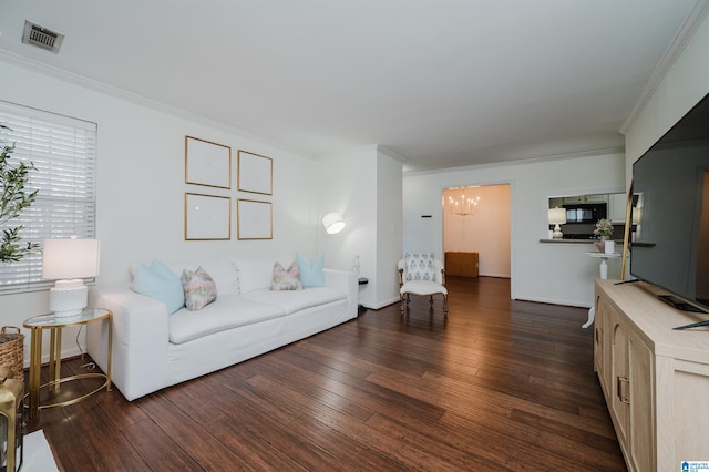 living room featuring crown molding, dark hardwood / wood-style flooring, and an inviting chandelier