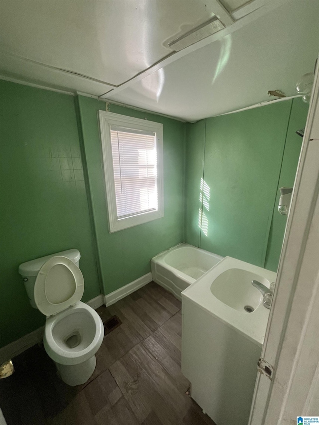 bathroom with a bathing tub, hardwood / wood-style floors, vanity, and toilet