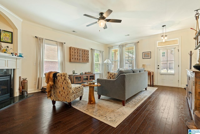 living room featuring ceiling fan, dark hardwood / wood-style flooring, crown molding, and a tile fireplace