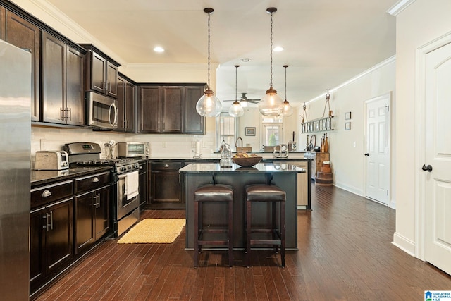 kitchen featuring pendant lighting, stainless steel appliances, dark stone counters, a breakfast bar, and dark brown cabinets