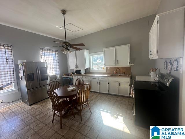 kitchen featuring stainless steel fridge, black electric range oven, ceiling fan, sink, and white cabinetry