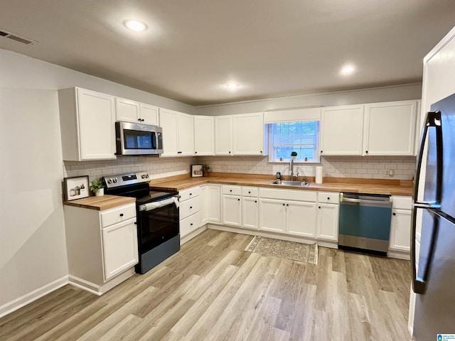 kitchen featuring sink, white cabinetry, butcher block counters, and stainless steel appliances