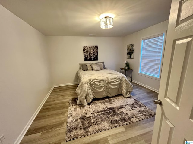 bedroom with an inviting chandelier and wood-type flooring