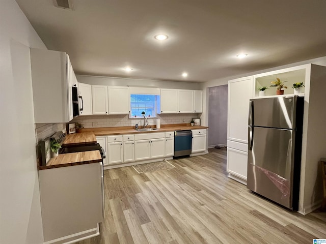 kitchen with butcher block countertops, sink, light wood-type flooring, appliances with stainless steel finishes, and white cabinets