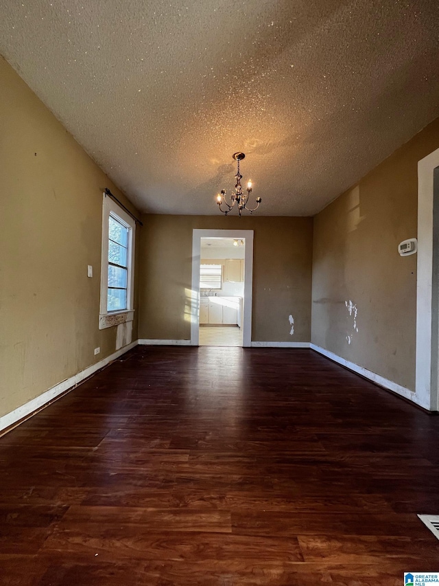 unfurnished room with dark hardwood / wood-style floors, an inviting chandelier, and a textured ceiling