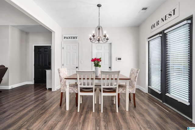 dining space with dark hardwood / wood-style floors and a notable chandelier