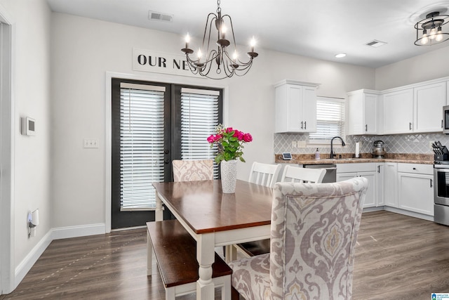 dining space featuring a notable chandelier, dark hardwood / wood-style flooring, sink, and french doors