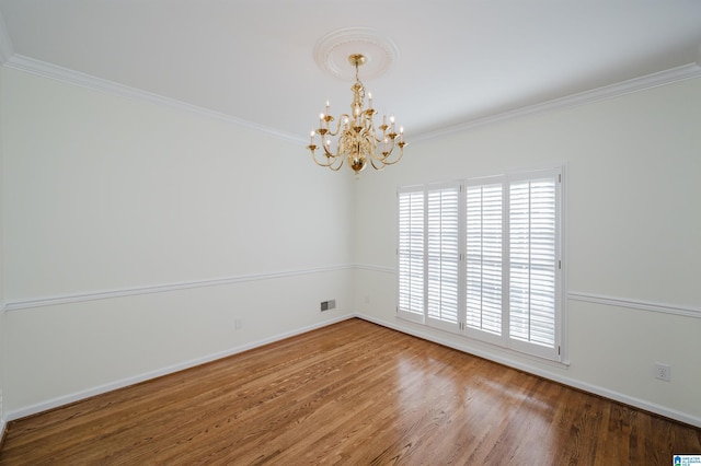 empty room featuring hardwood / wood-style flooring, ornamental molding, and an inviting chandelier