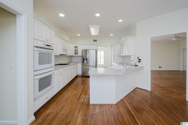 kitchen featuring white appliances, sink, kitchen peninsula, ornamental molding, and white cabinetry