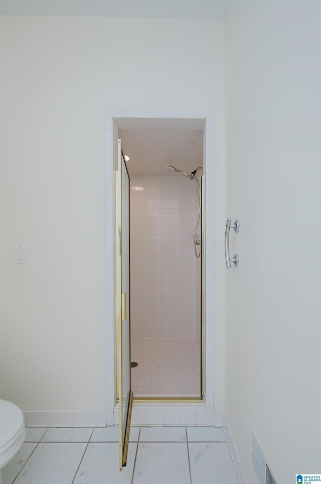 bathroom featuring tile patterned flooring, toilet, and walk in shower