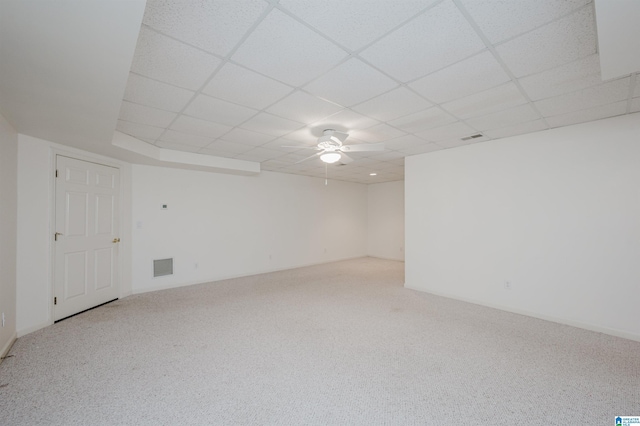 empty room featuring a paneled ceiling, light colored carpet, and ceiling fan