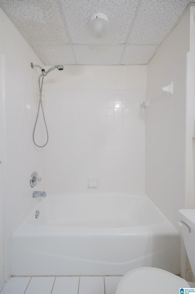 bathroom with tile patterned flooring, a paneled ceiling, toilet, and tiled shower / bath