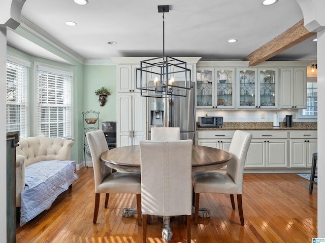 dining room featuring beam ceiling, light hardwood / wood-style floors, an inviting chandelier, and crown molding