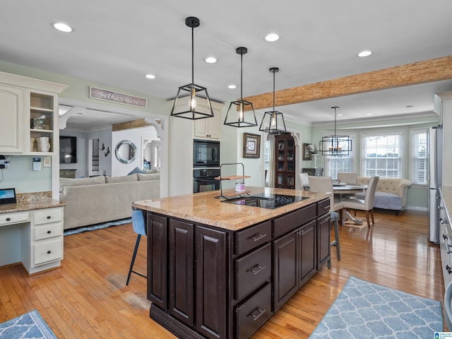 kitchen featuring pendant lighting, black appliances, white cabinetry, a breakfast bar area, and dark brown cabinets