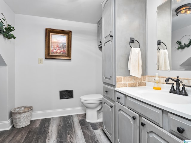 bathroom with toilet, hardwood / wood-style flooring, backsplash, and vanity