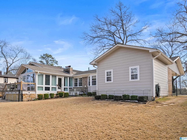 rear view of house featuring a lawn and a sunroom