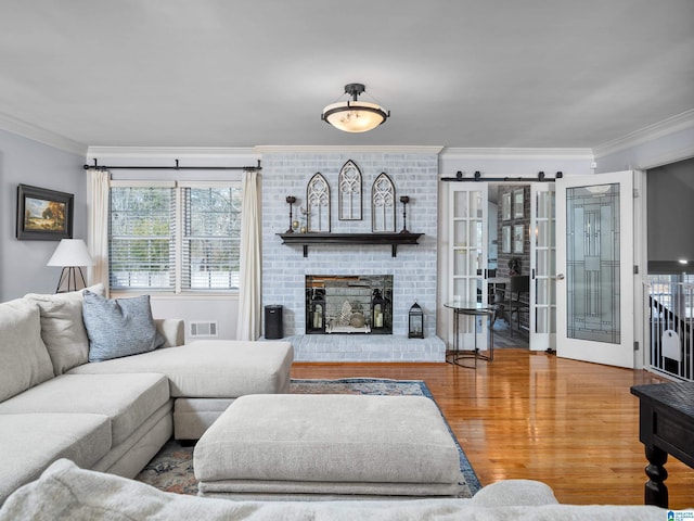 living room featuring hardwood / wood-style flooring, french doors, ornamental molding, and a fireplace