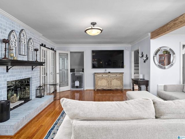 living room with a brick fireplace, hardwood / wood-style floors, and crown molding