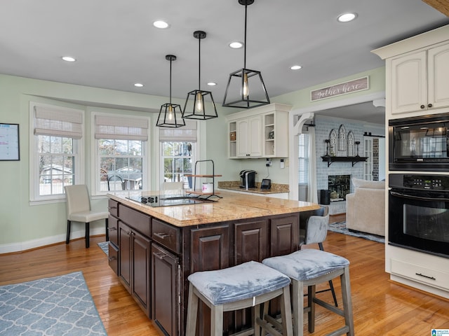 kitchen featuring white cabinets, black appliances, dark brown cabinets, and light hardwood / wood-style flooring