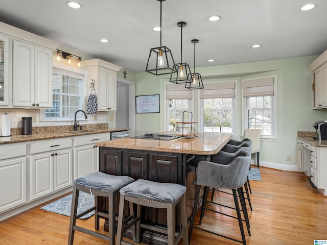 kitchen featuring pendant lighting, a center island, decorative backsplash, white cabinets, and sink